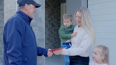A man is giving a gift to a woman and two children.