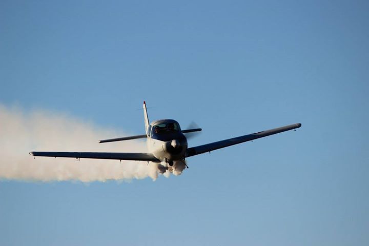 A small propeller plane is flying through a clear blue sky.