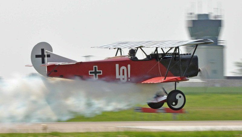 A red and white airplane is taking off from an airport runway.