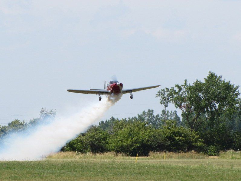 A small plane is taking off from a runway with smoke coming out of its wings.