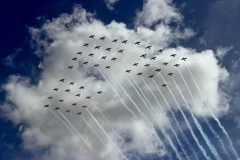 A flock of planes are flying in formation in the sky