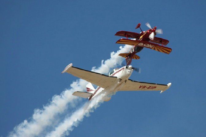 Two airplanes are flying in the sky and one of them has the letters vp on the tail