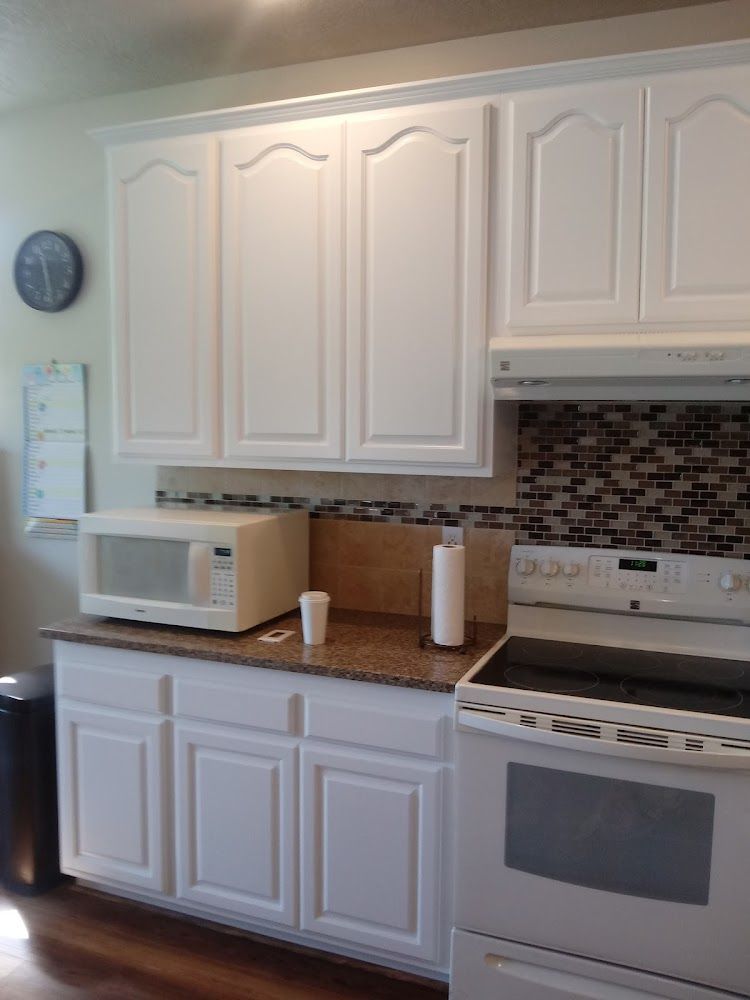 A kitchen with white cabinets and a stove and microwave