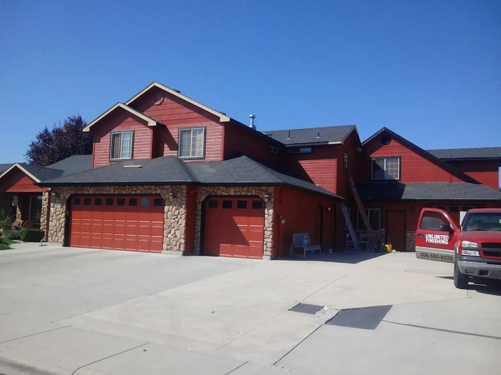 A red truck is parked in front of a large red house