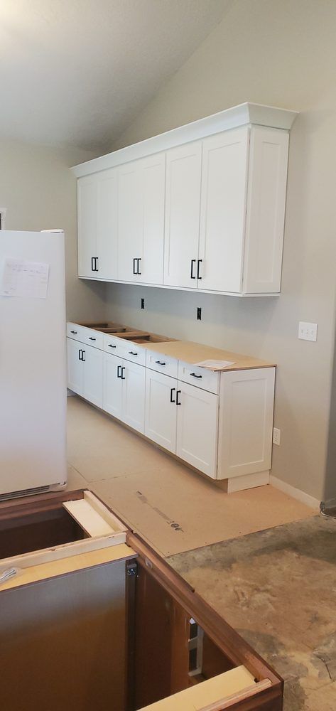 A kitchen under construction with white cabinets and a sink.