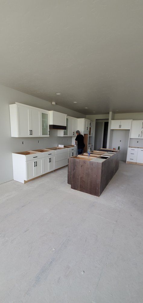 A man is standing in a kitchen with white cabinets and a large island.