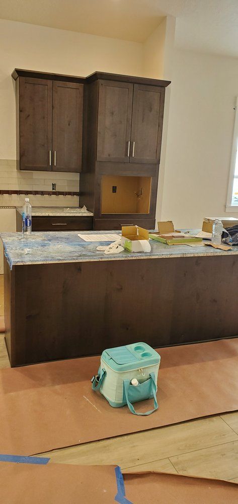 A kitchen under construction with a large island and a cooler on the floor.