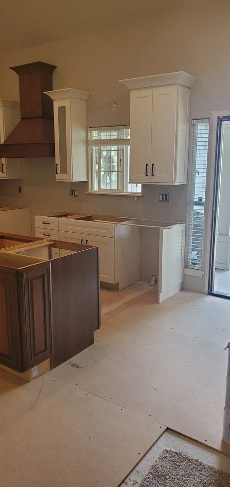 A kitchen with white cabinets and brown cabinets is being remodeled.