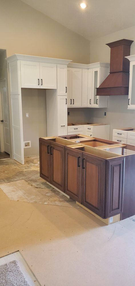 A kitchen with white cabinets and brown cabinets is being remodeled.