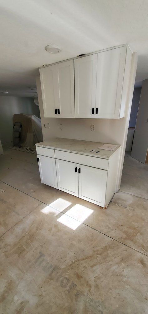 A kitchen with white cabinets and a concrete floor.