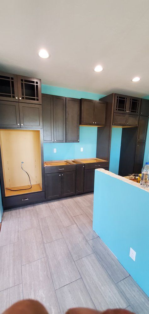 A kitchen with blue walls and black cabinets is being remodeled.