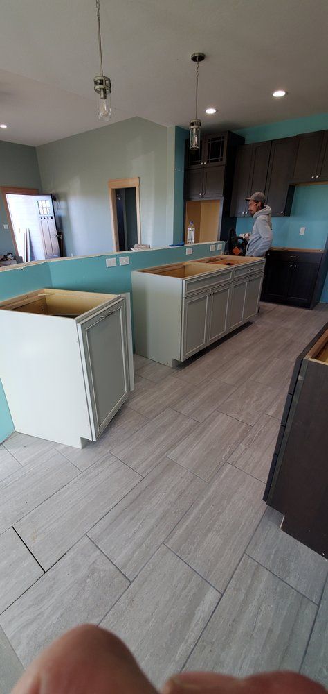 A man is standing in a kitchen with a lot of cabinets.