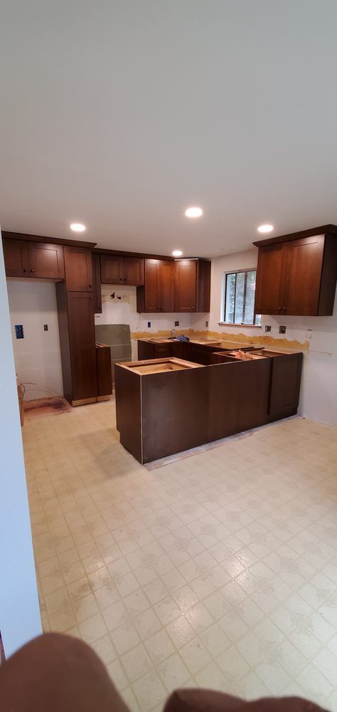 A kitchen with wooden cabinets and a large island in the middle of the room.