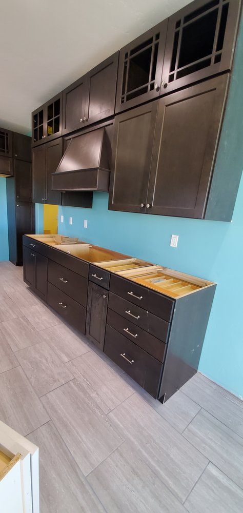 A kitchen with a lot of cabinets and drawers and a blue wall.