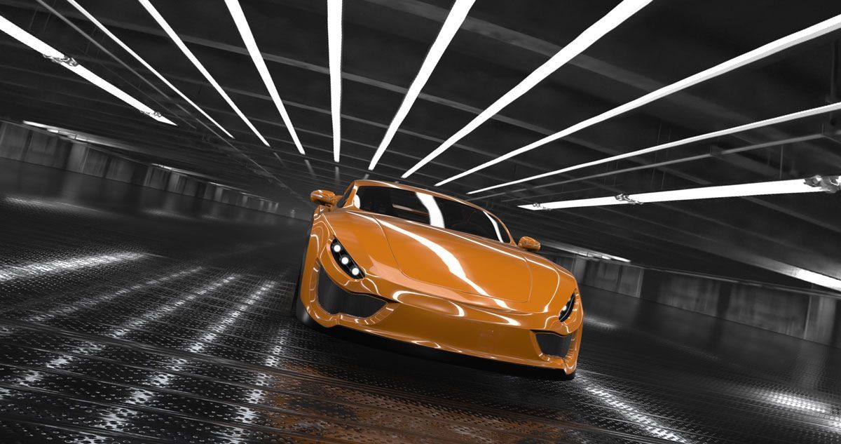 Orange sports car speeding through a tunnel, with bright overhead lights reflecting on the wet asphalt.