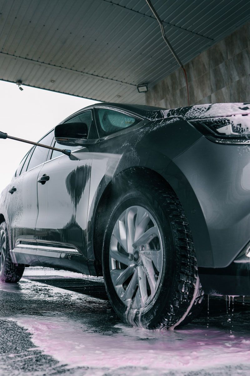 Car being washed at a car wash with pink soap suds.