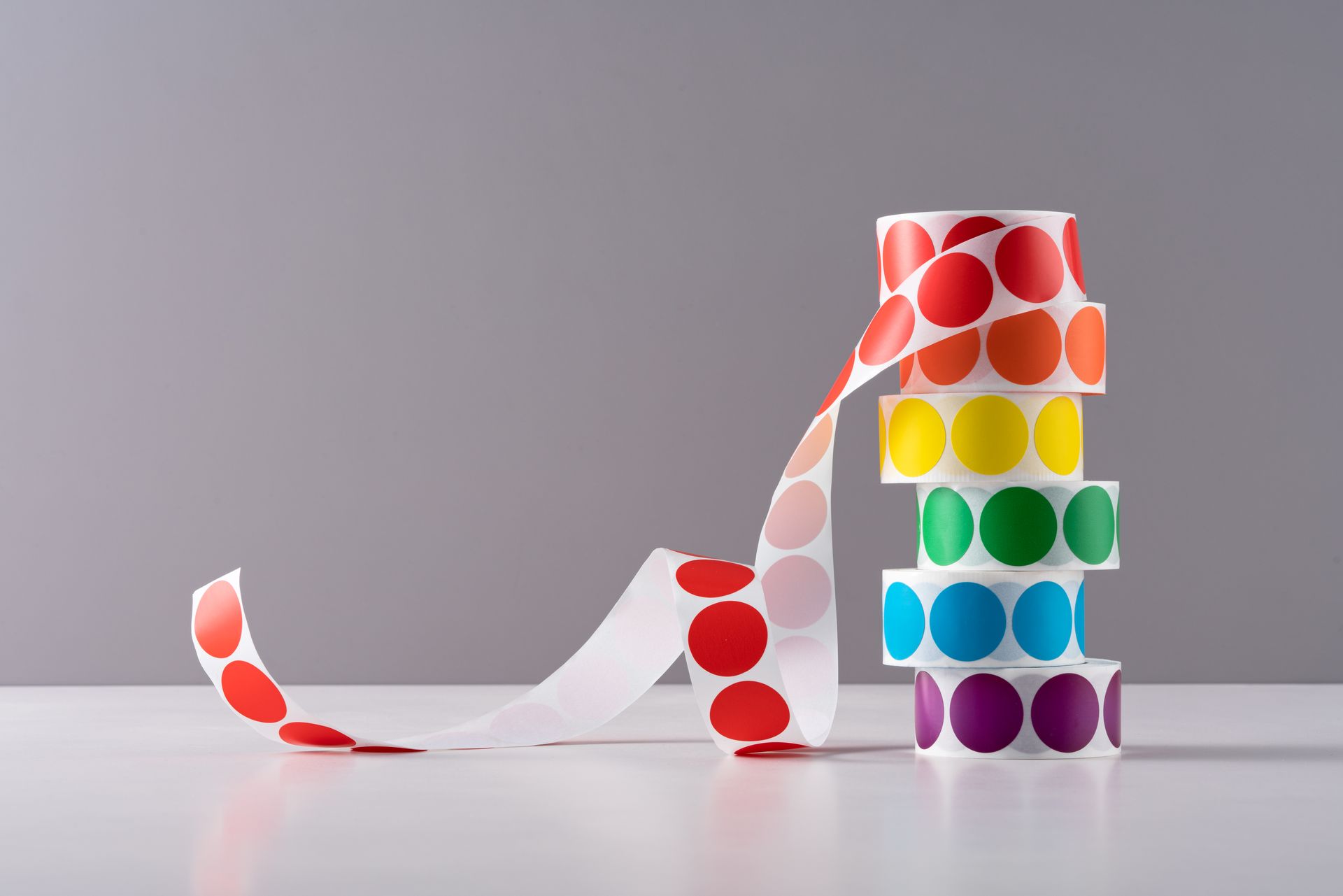 Un rotolo di adesivi colorati è impilato uno sopra l'altro su un tavolo.