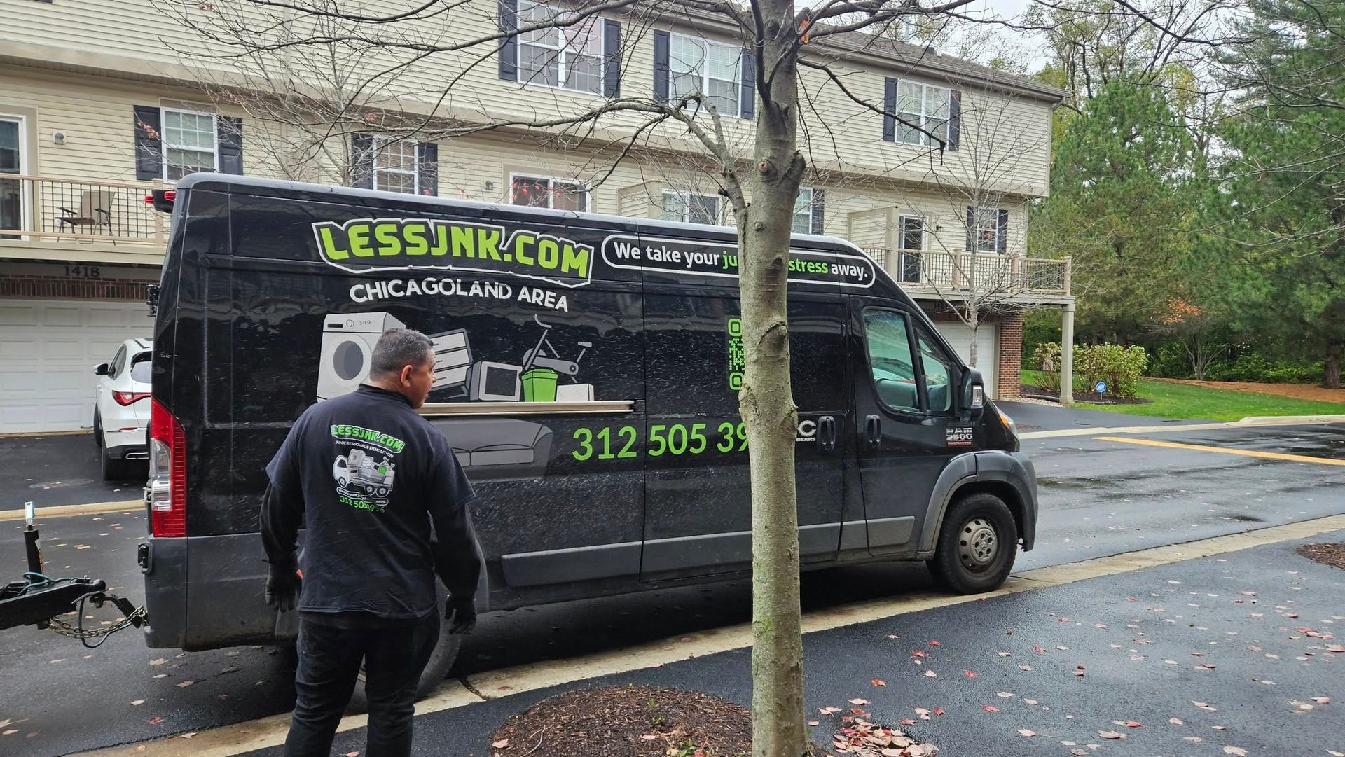 A man is standing in front of a black van that says lesssink.com on it.