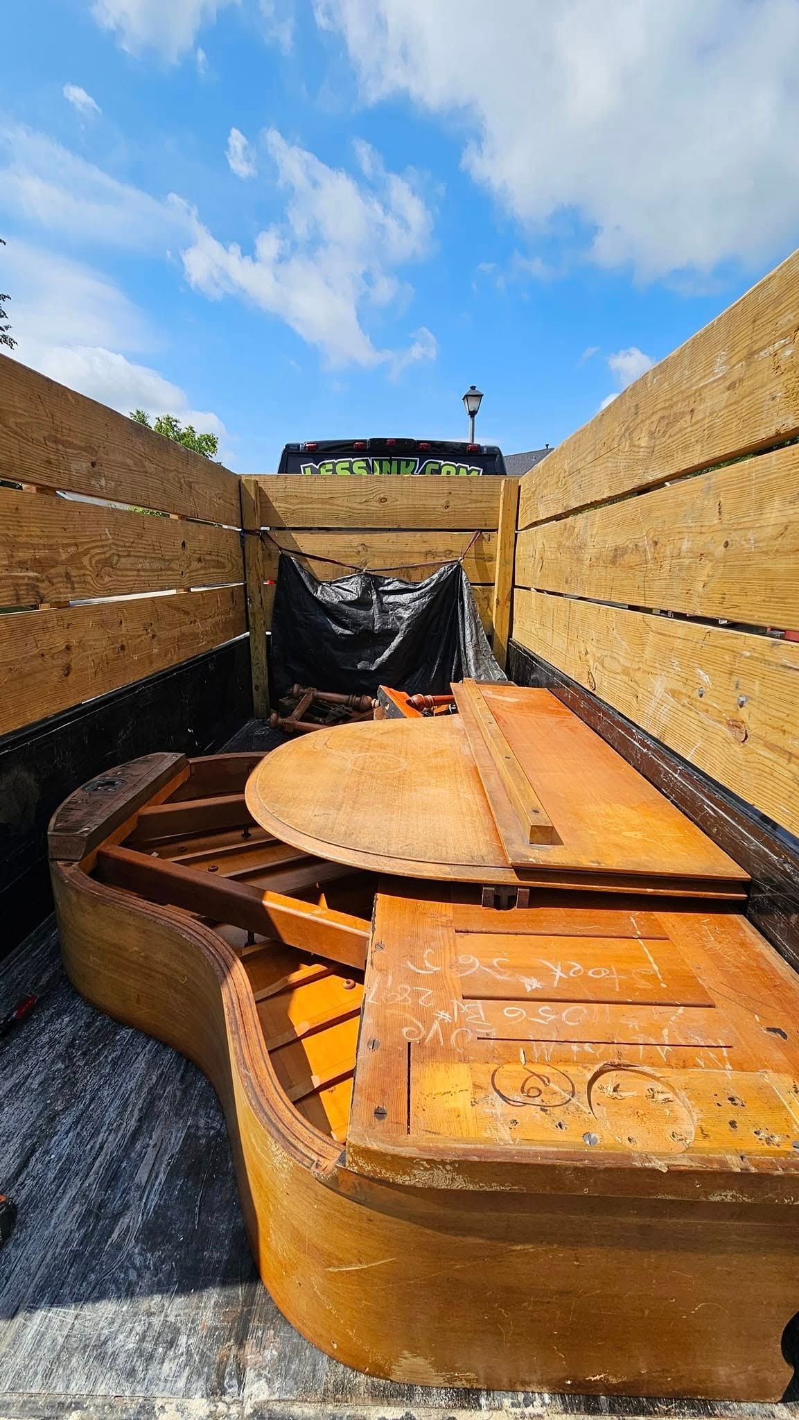 A large wooden piano is sitting in the back of a truck.