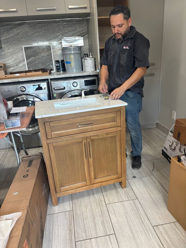 GAL Plumbing Service | man is standing next to a sink in a kitchen.