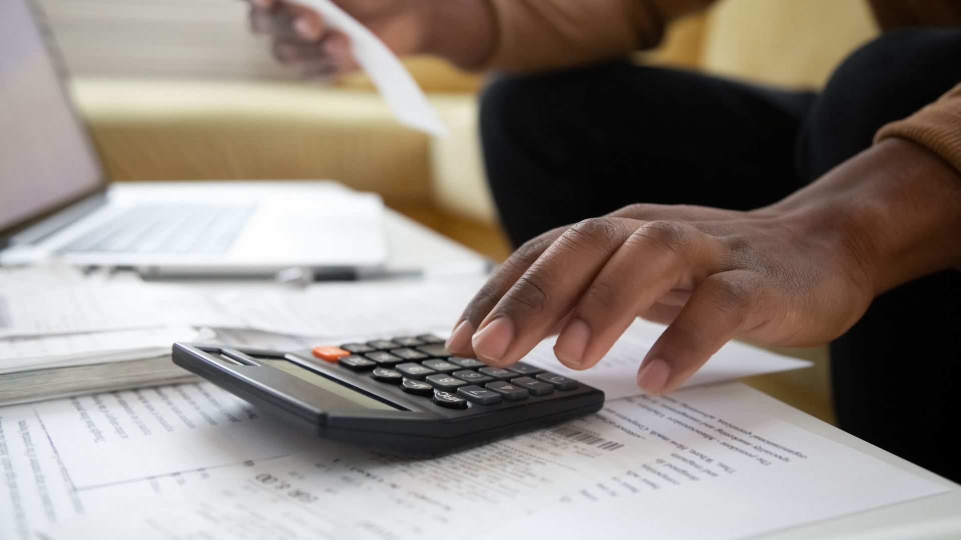 A person is using a calculator while holding a piece of paper.