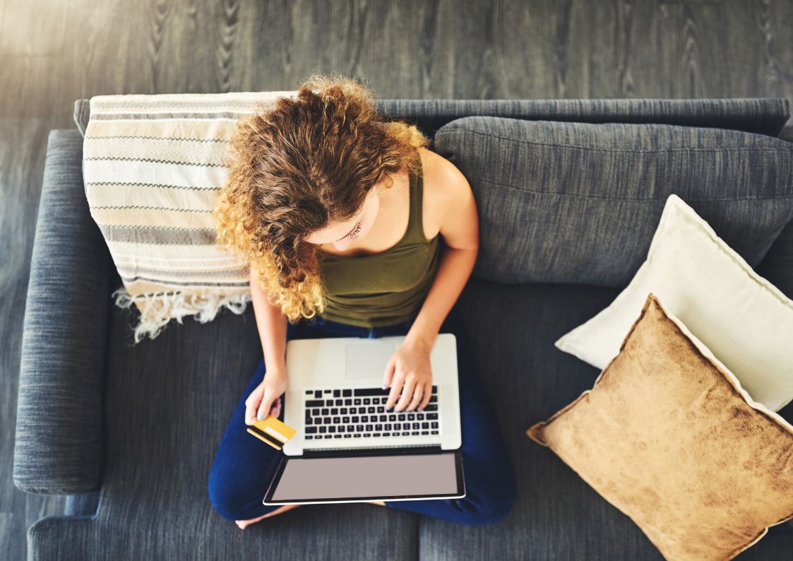 A woman is sitting on a couch using a laptop computer.