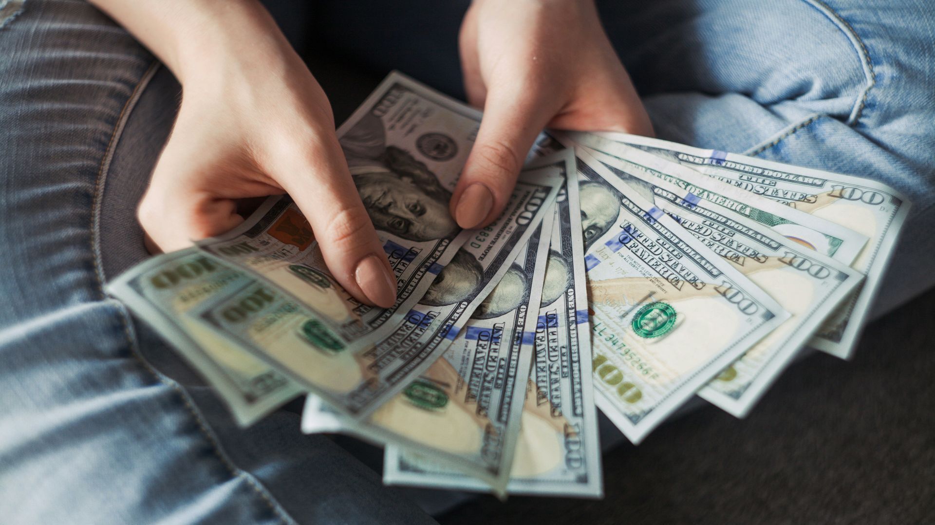 A person is holding a bunch of money in their hands.