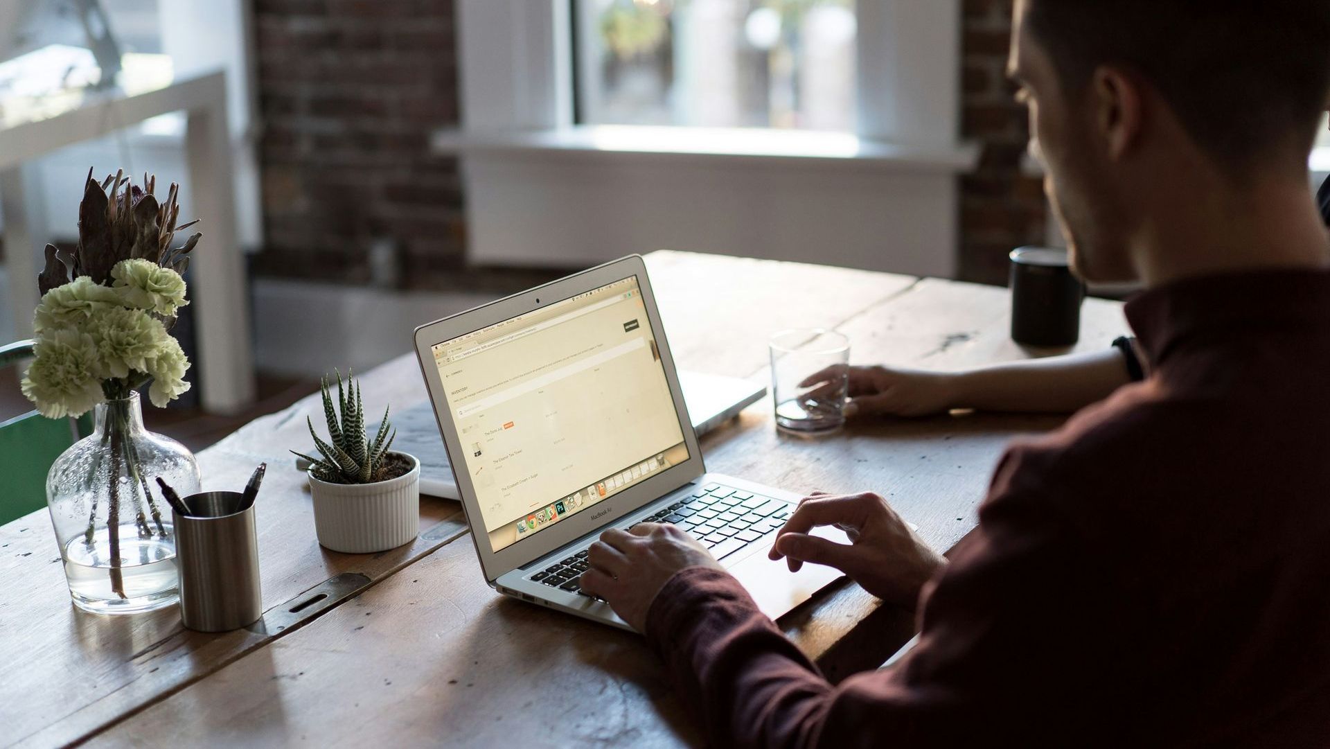 A man is sitting at a table using a laptop computer.