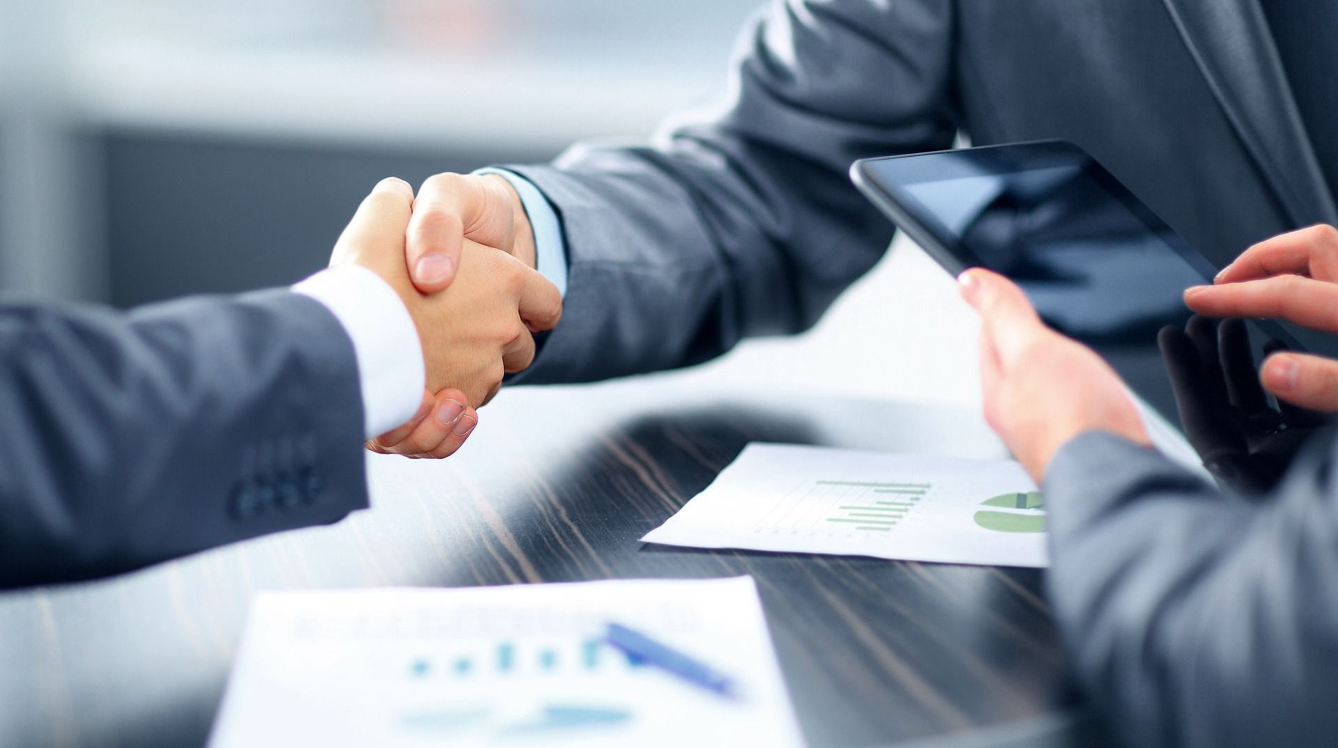 Two businessmen are shaking hands over a table.
