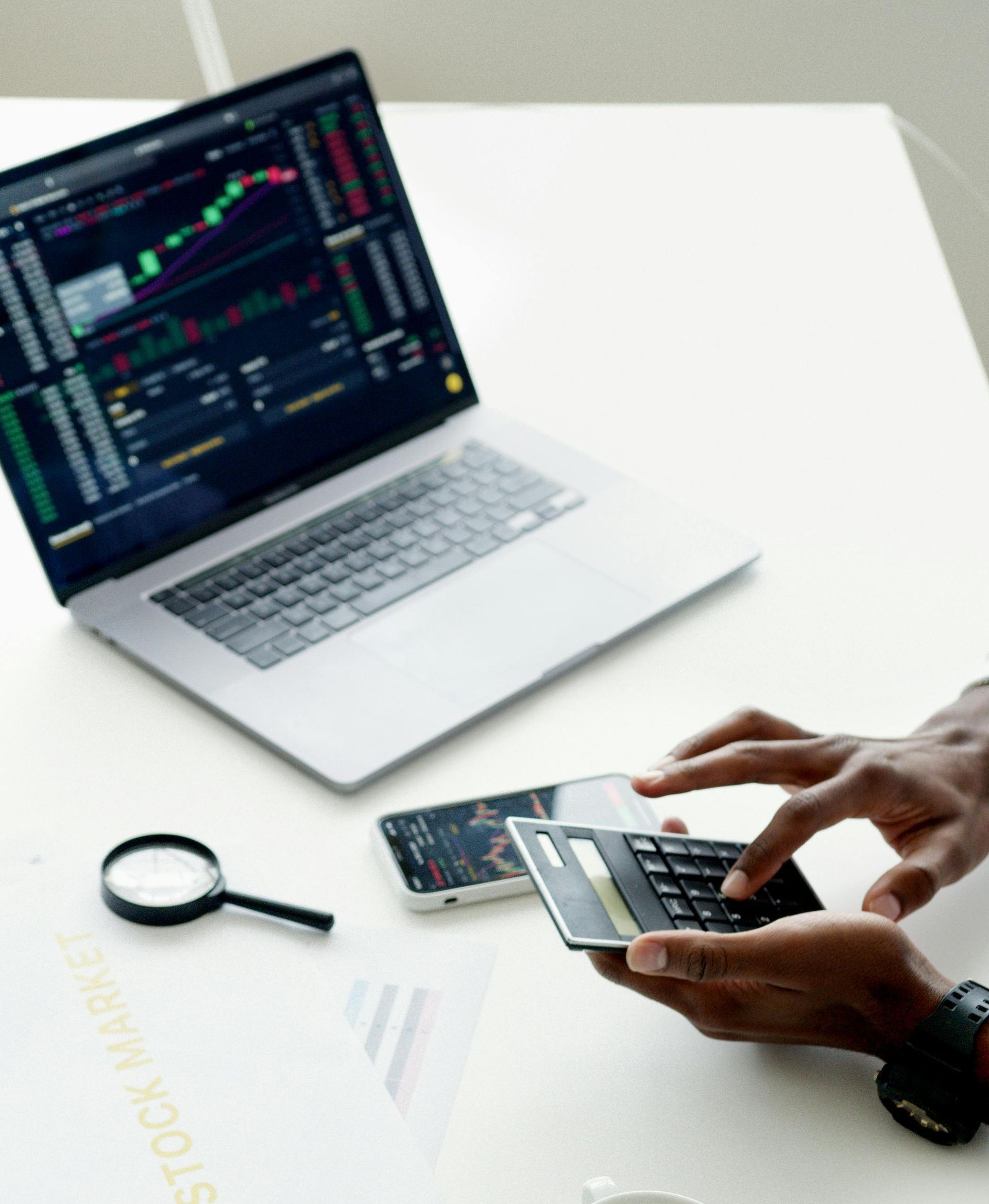 A person is using a calculator in front of a laptop