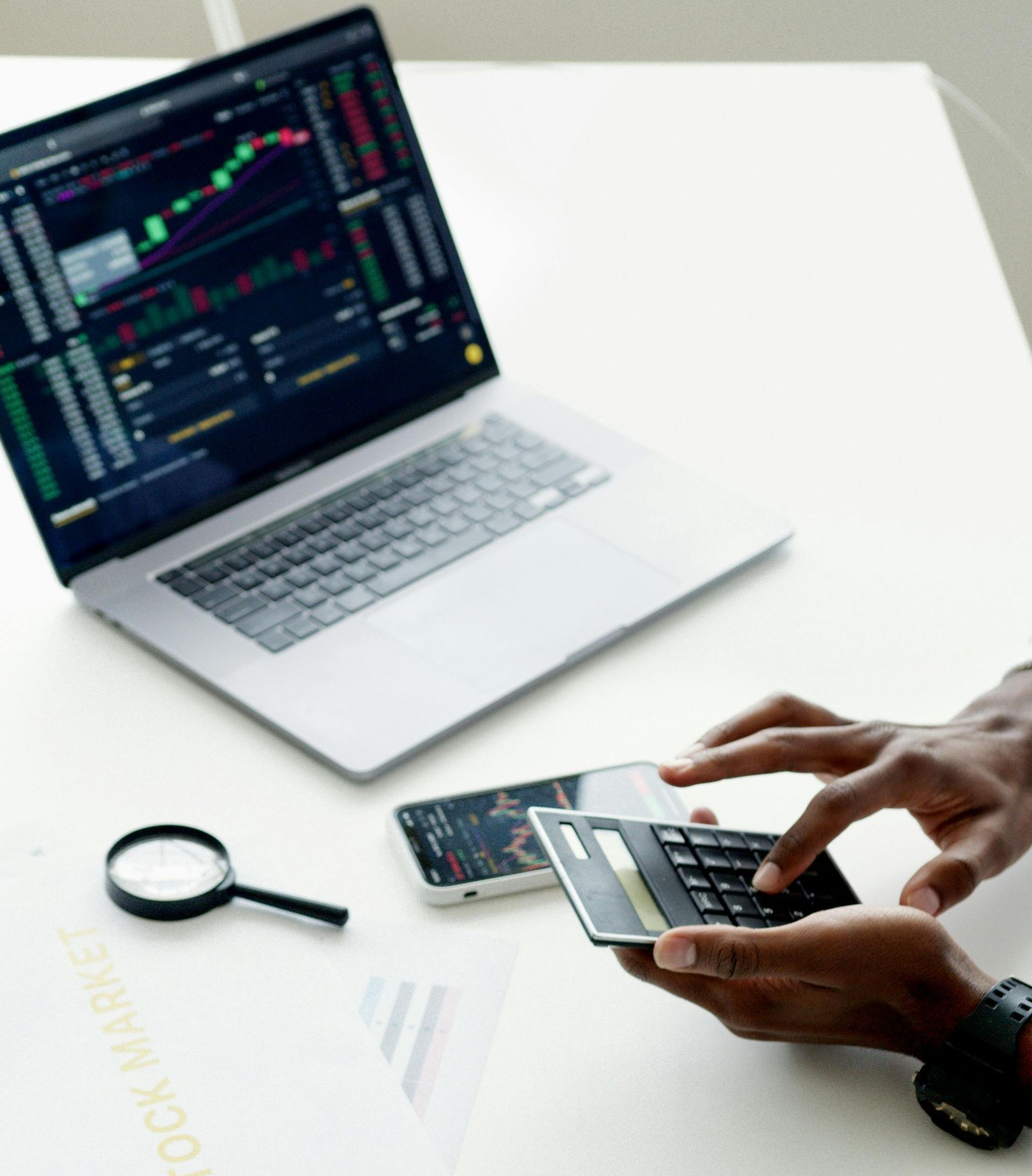 A person is using a calculator in front of a laptop