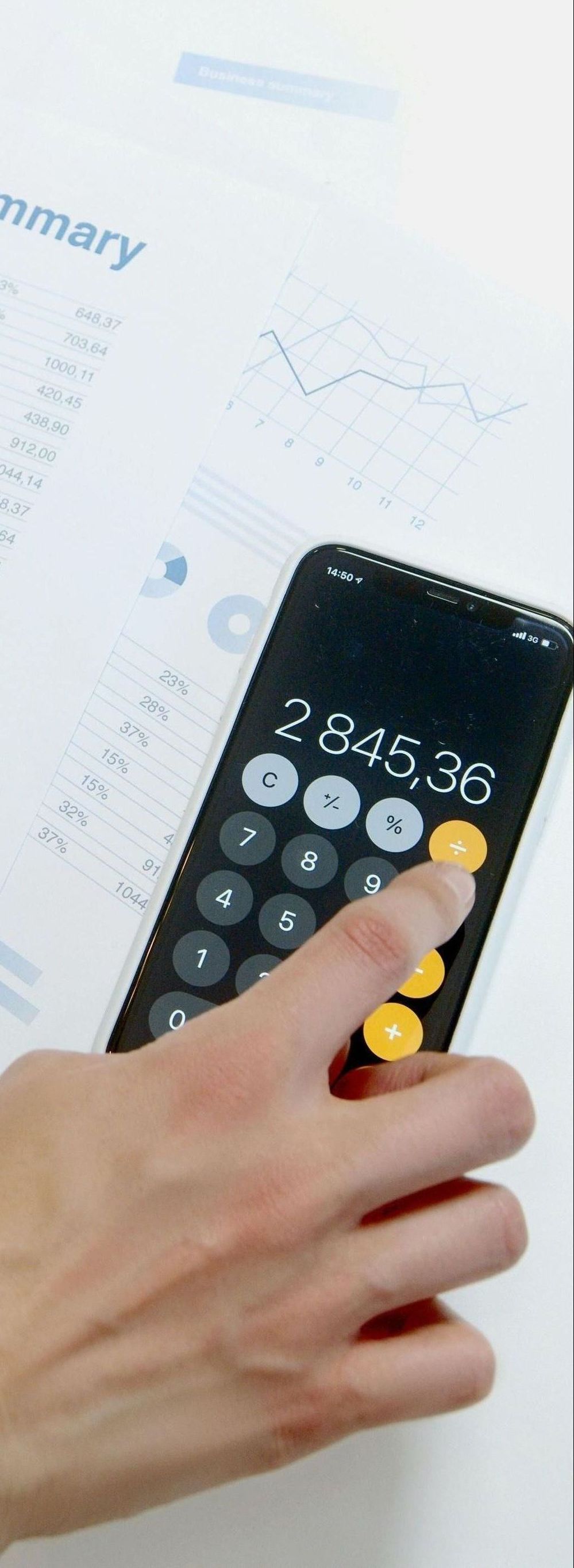 A person is using a calculator on a table.