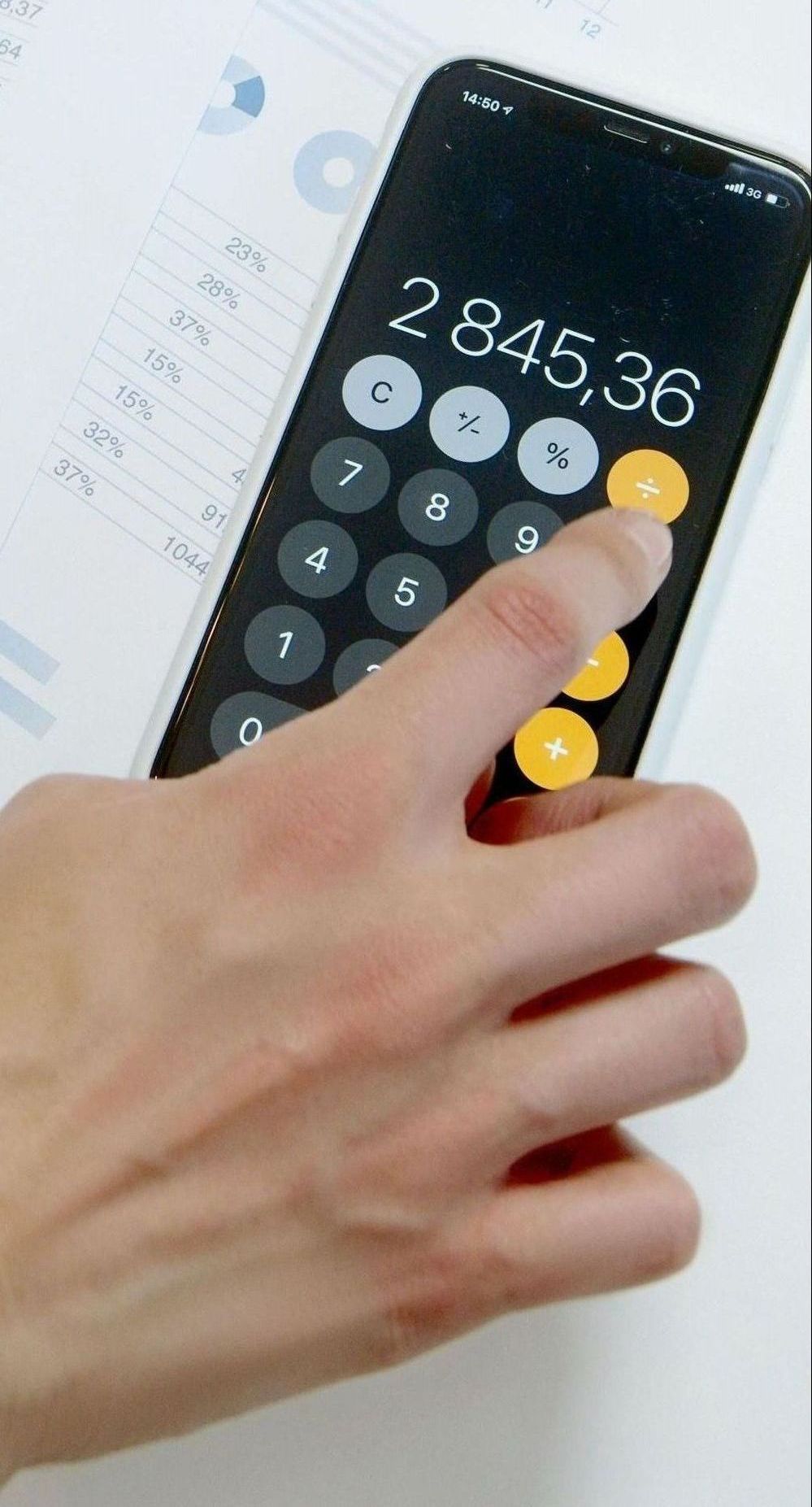 A person is using a calculator on a table.