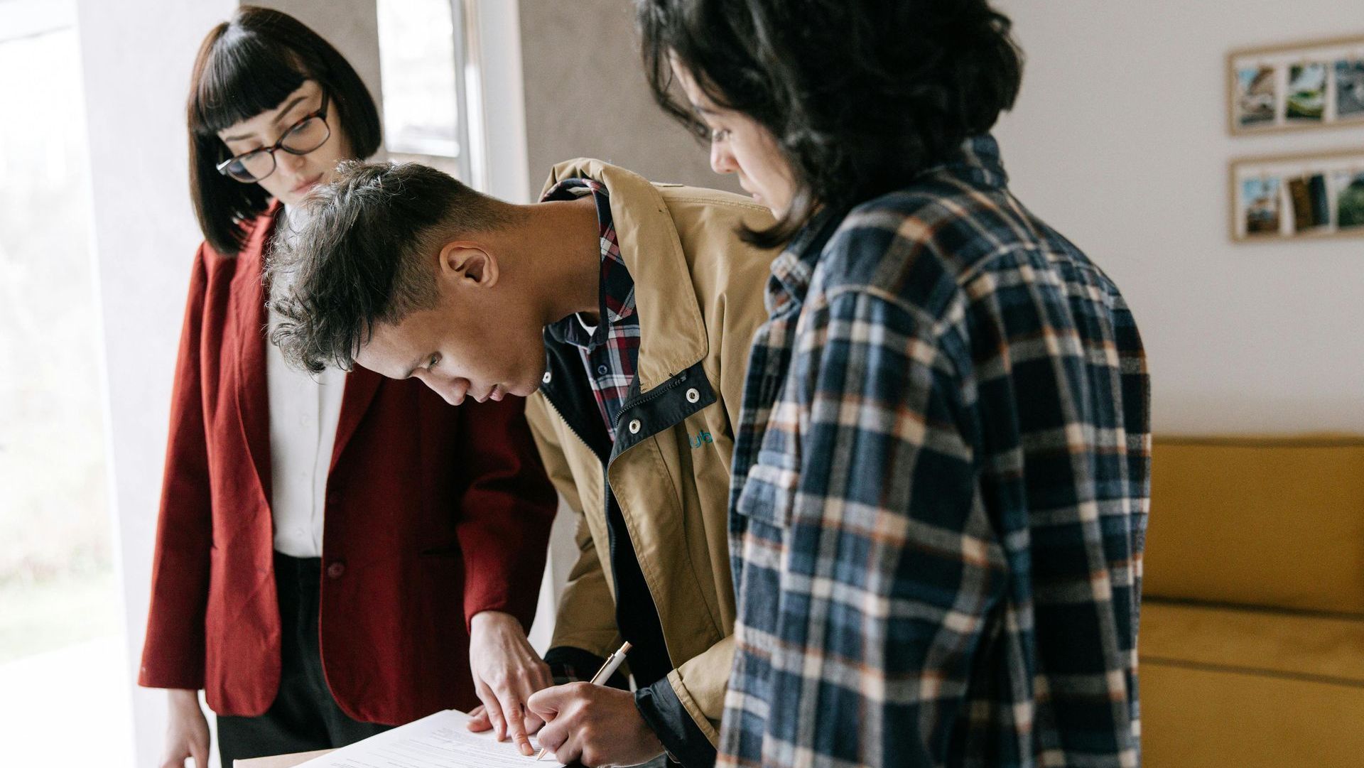 A group of people are signing a document in a living room.