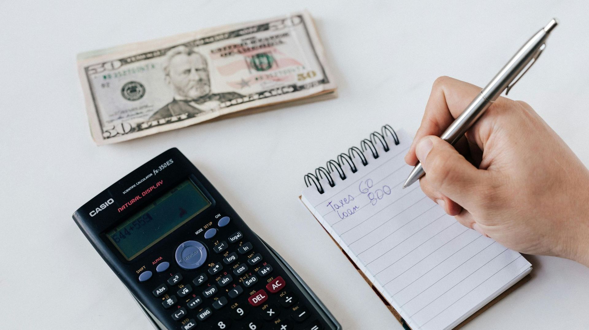 A person is using a calculator while holding a piece of paper.