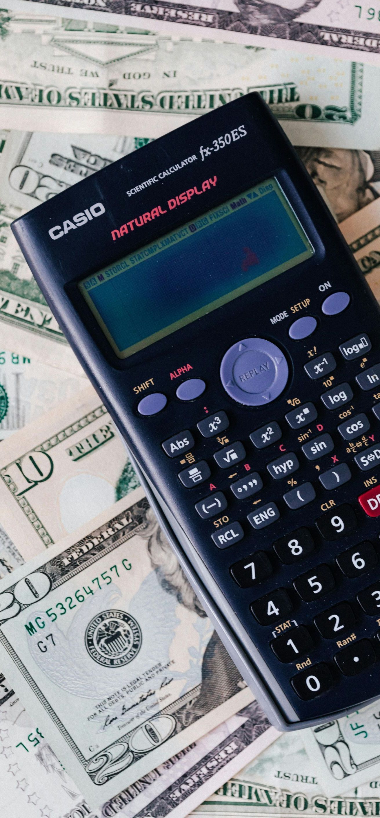 A calculator is sitting on top of a pile of money.