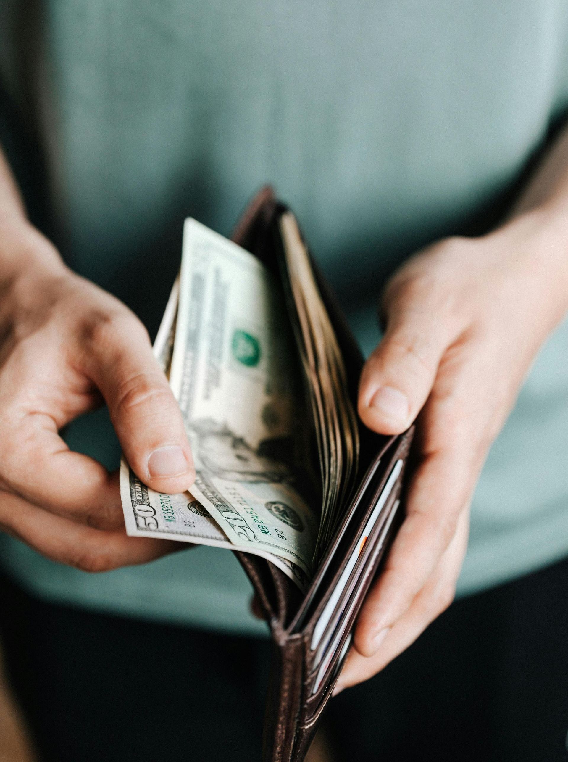 A person is holding a wallet with money in it.
