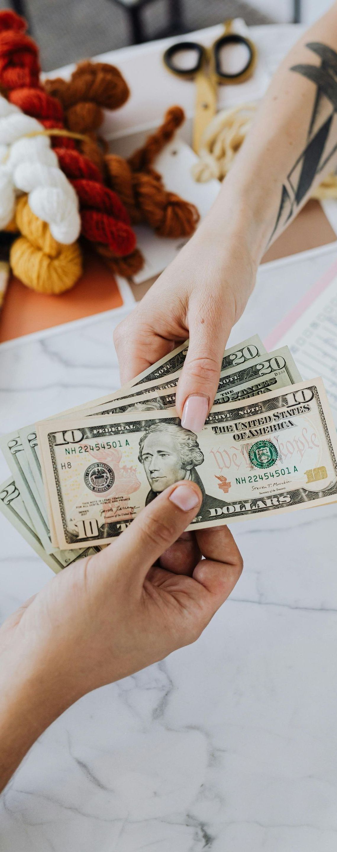 A woman is handing a stack of money to another woman.