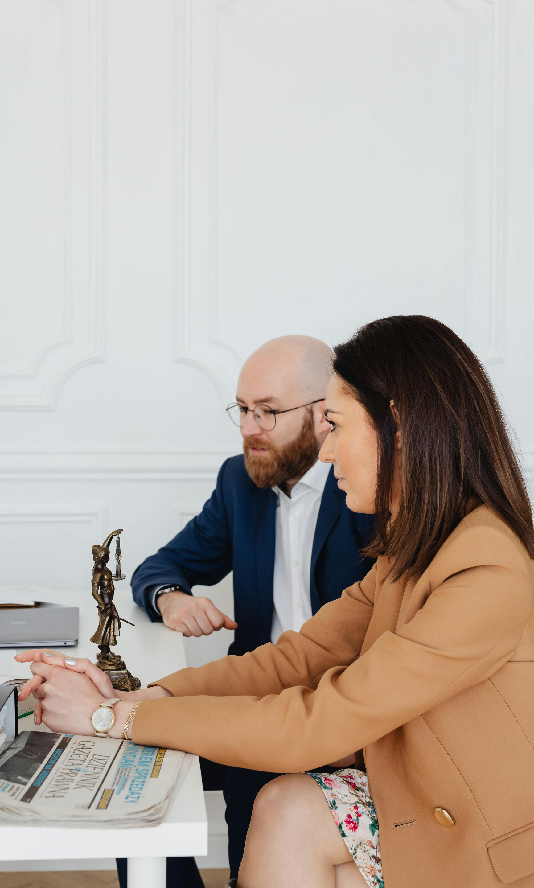 Two professionals in a legal office reviewing a laptop; man in suit, woman in blazer.