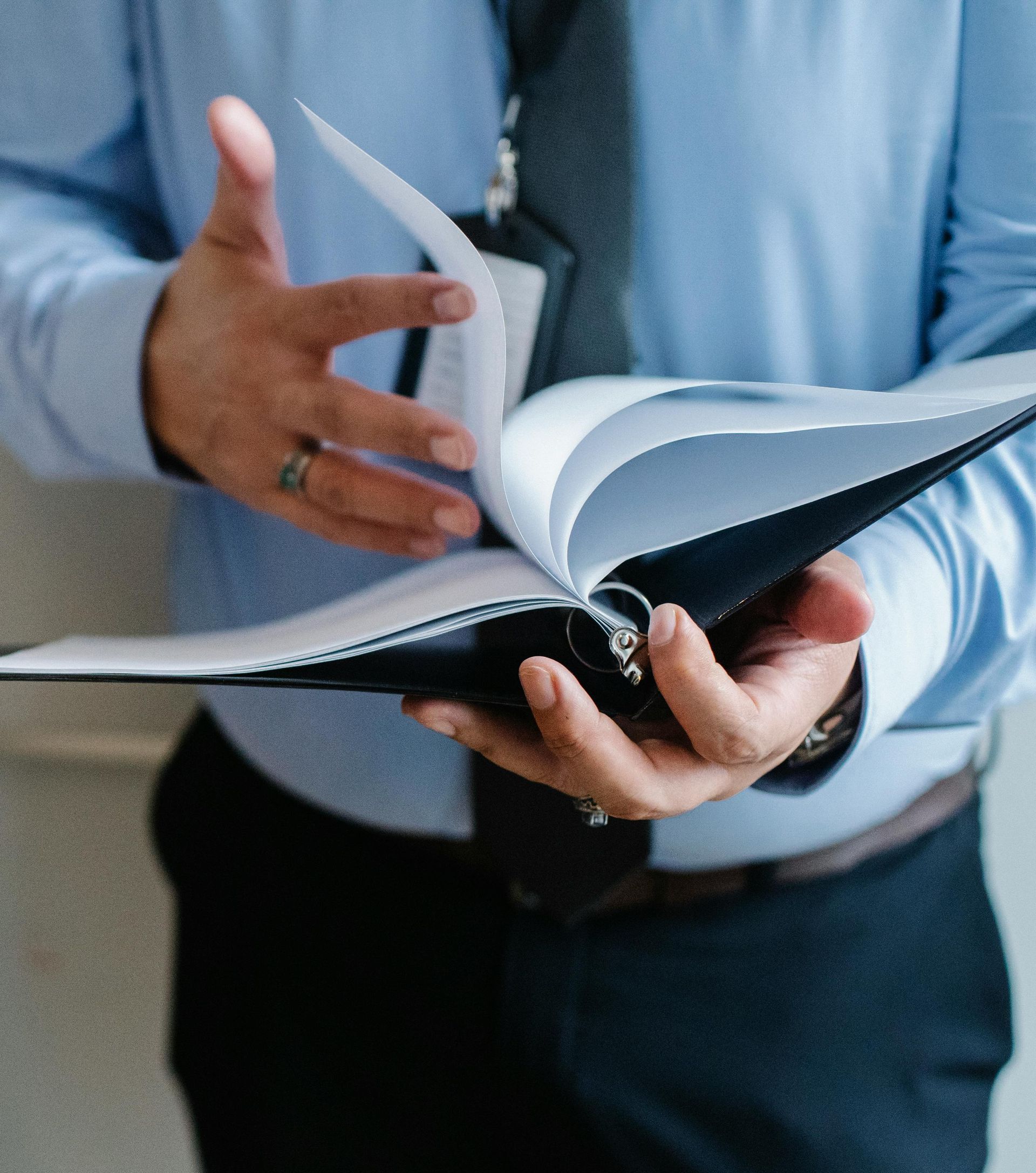 A man in a blue shirt is holding a binder in his hands