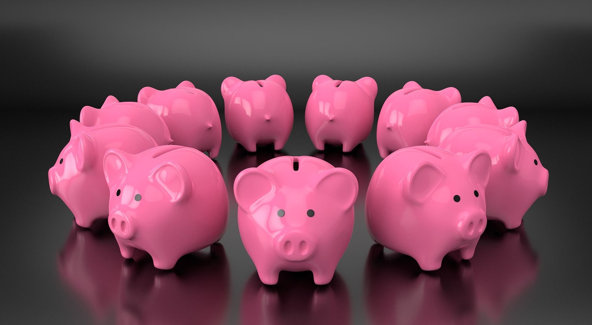 A group of pink piggy banks are sitting in a circle on a black surface.