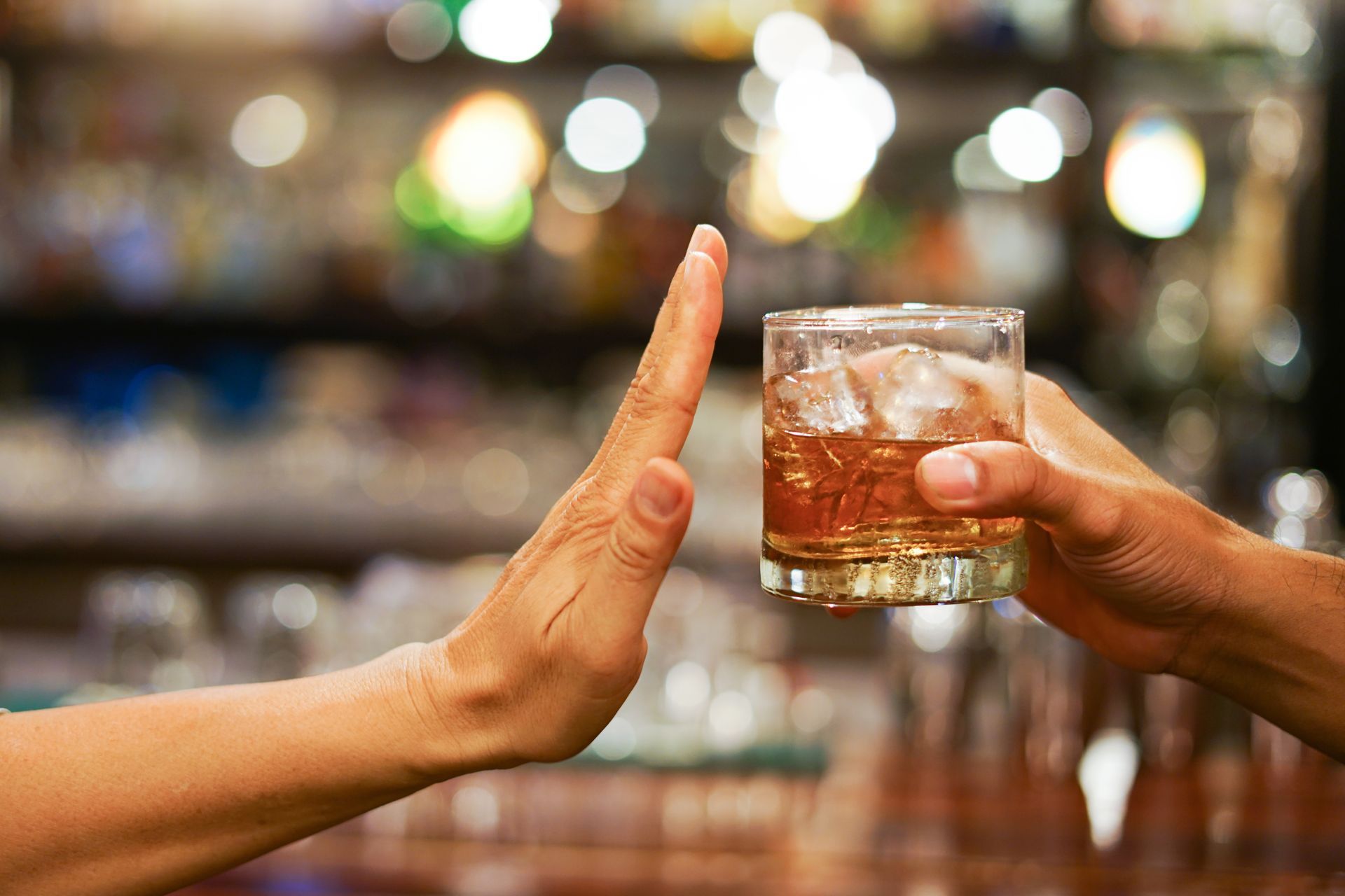 Man refusing alcohol at a table, symbolizing a commitment to recovery and saying no to addiction