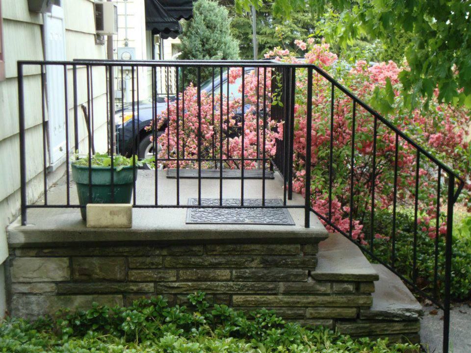 A porch with a wrought iron railing and steps