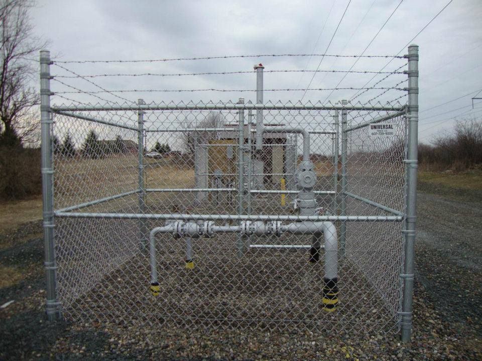 A chain link fence with barbed wire surrounding a gas station