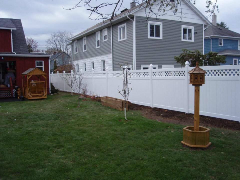 A backyard with a white fence and a birdhouse