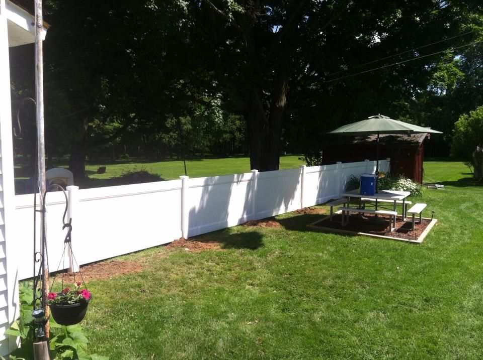 A backyard with a white fence and a picnic table