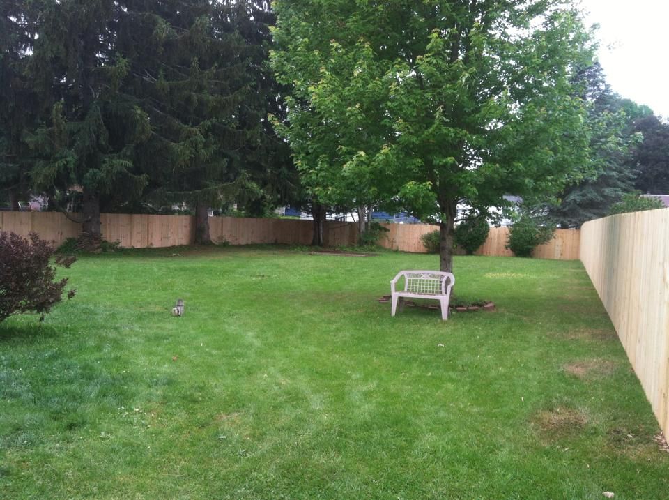 A backyard with a wooden fence and a white chair