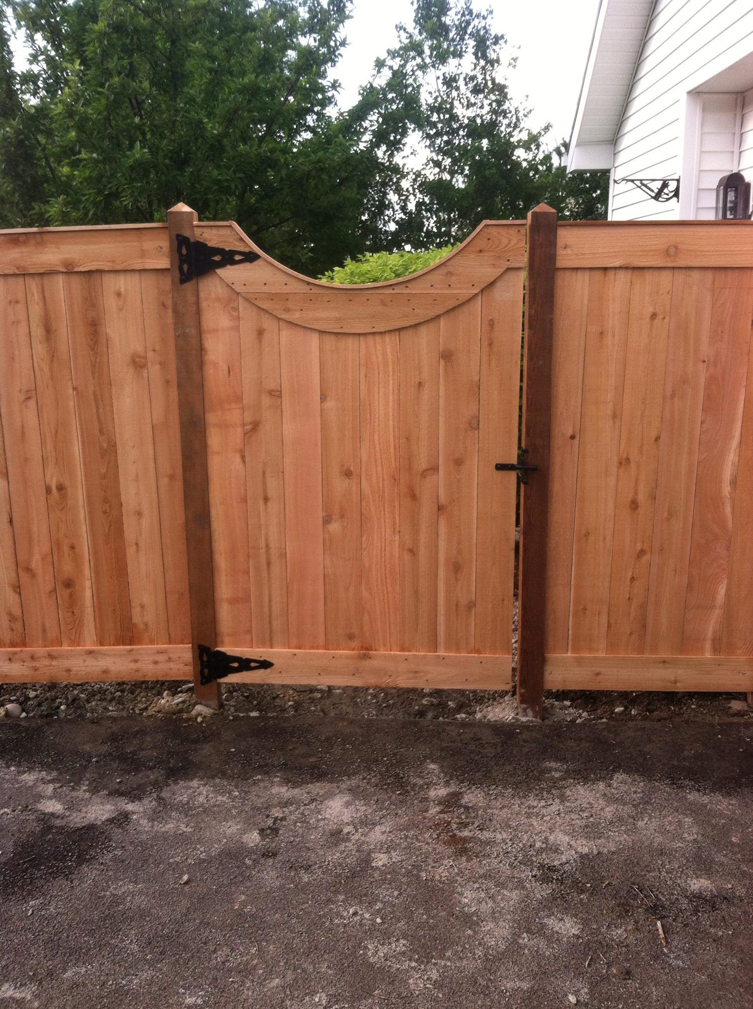 A wooden fence with a gate in front of a house.