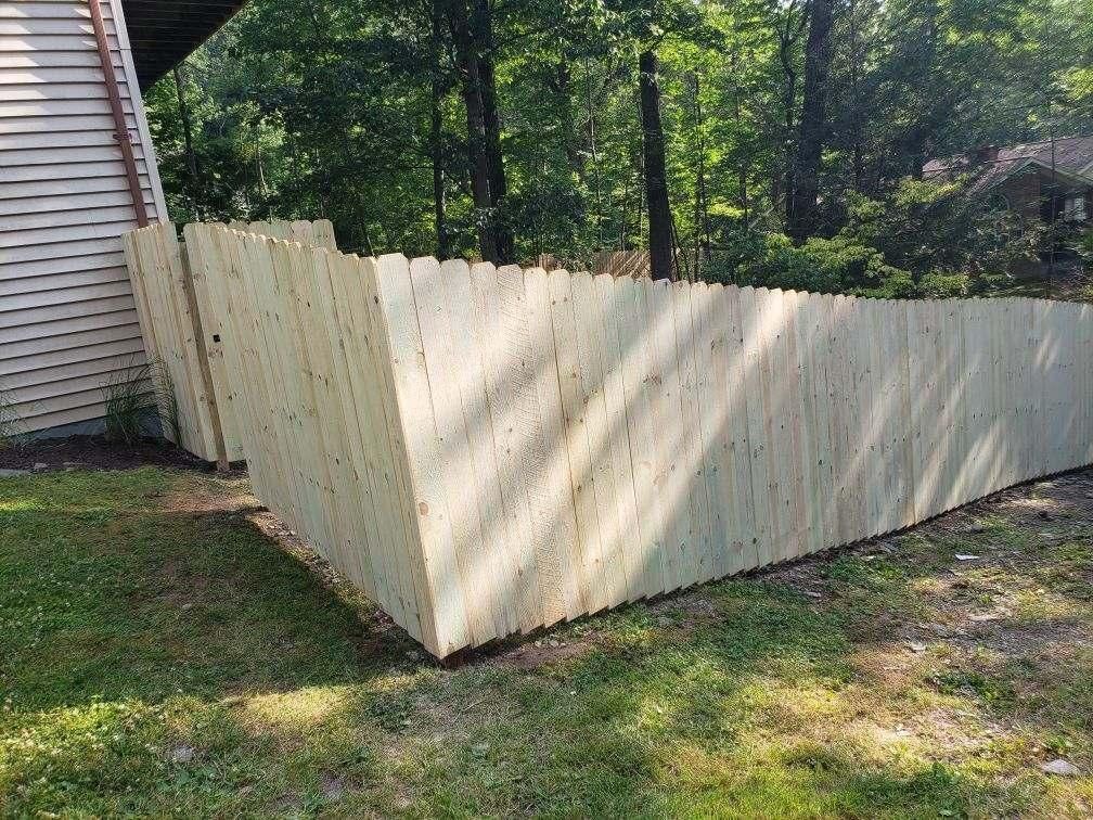 A wooden fence is sitting in the grass in front of a house.