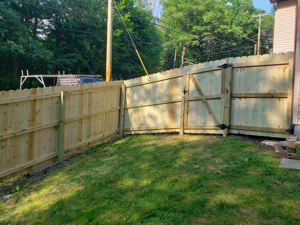 A wooden fence with a gate in the backyard of a house.